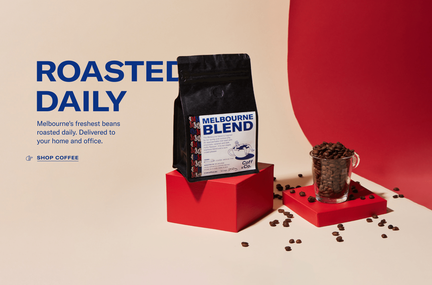 Melbourne Blend bag on a red plinth beside a glass of roasted beans, warm studio photograph
